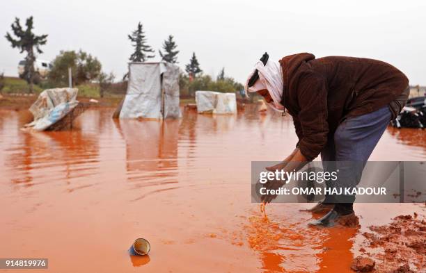 Abu Khaled washes his hands in a large puddle of rain water at make-shift camp for internally displaced people in Batabu, on the border between...