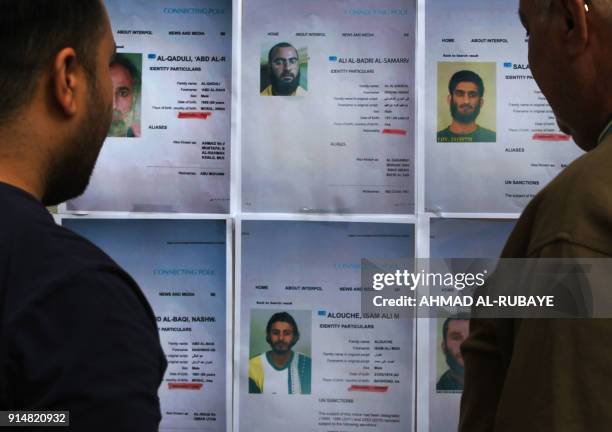 Iraqis look at printed profiles of Islamic State group members released by Iraqi authorities on February 6, 2018. Iraqi authorities issued a new list...