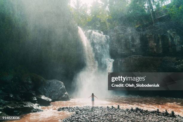 woman standing near   tegenungan waterfall in bali, indonesia - bali waterfall stock pictures, royalty-free photos & images