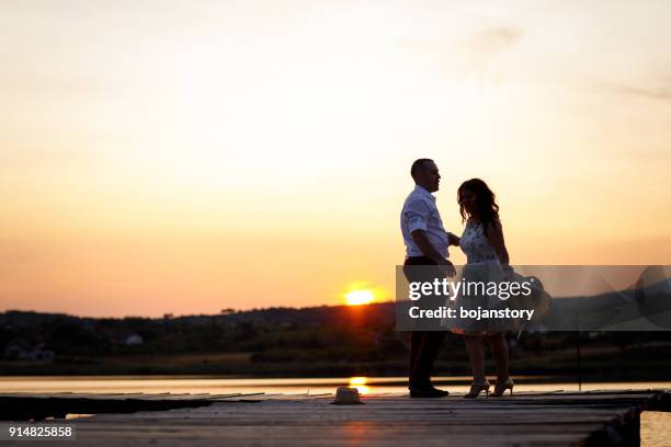 young couple dancing on jetty at sunset - silhouette danceur stock pictures, royalty-free photos & images