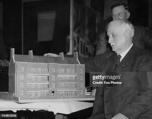British Labour politician and social reformer George Lansbury , the MP for Bow and Bromley, examines a model of a block of flats built by the Stepney...
