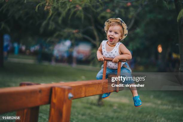 niño feliz divirtiéndose en un sube y baja en el parque. - sólo niños varones fotografías e imágenes de stock