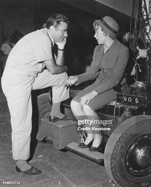 British actor Peter Lawford listens to co-star Shirley MacLaine on a movie set, circa 1960.