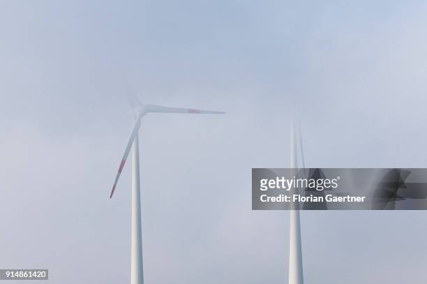 Two wind turbines in the fog are pictured on February 05, 2018 in Loebau, Germany.
