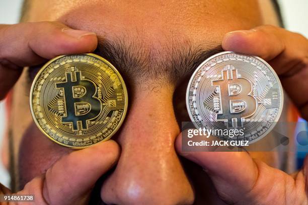 Picture taken on February 6, 2018 shows a person holding a visual representation of the digital crypto-currency Bitcoin, at the "Bitcoin Change" shop...