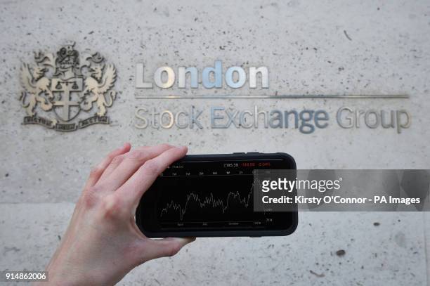 View of the Stocks app on an iPhone against the London Stock Exchange sign in the City of London, as the FTSE 100 Index crashed on opening by more...