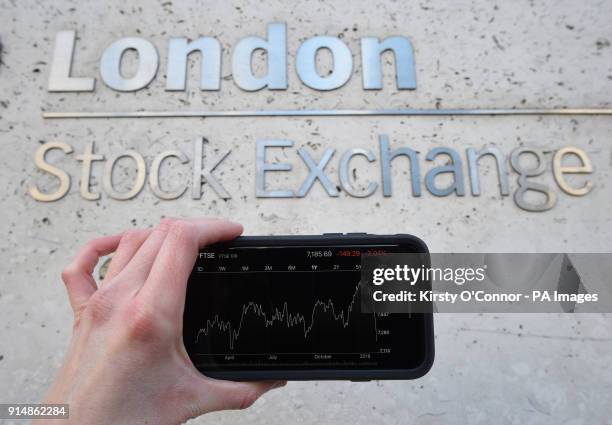 View of the Stocks app on an iPhone against the London Stock Exchange sign in the City of London, as the FTSE 100 Index crashed on opening by more...