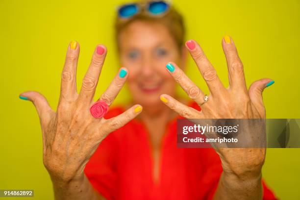 color surge for stylish seniors - happy senior woman showing her colorful fingernails - multi coloured nails stock pictures, royalty-free photos & images