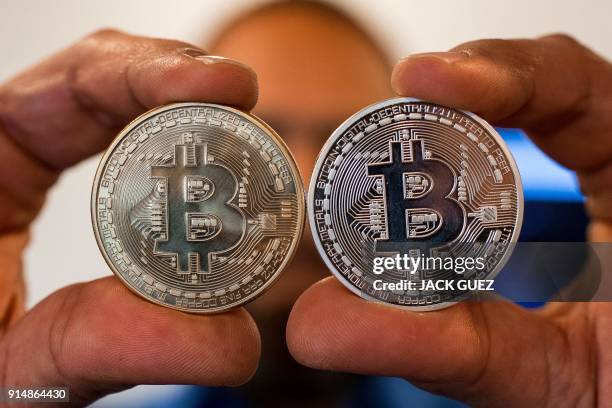 Picture taken on February 6, 2018 shows a person holding a visual representation of the digital crypto-currency Bitcoin, at the "Bitcoin Change" shop...