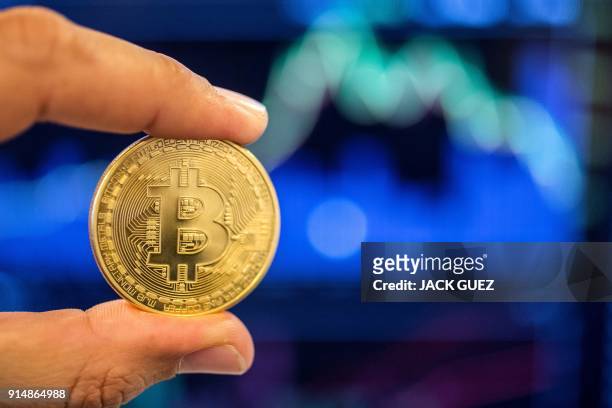 Picture taken on February 6, 2018 shows a person holding a visual representation of the digital crypto-currency Bitcoin, at the "Bitcoin Change" shop...