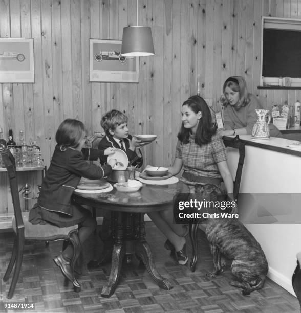 English actor Mark Lester, young star of the musical film version of 'Oliver!', asks for a second helping at his home, UK, 1967. With him are his...