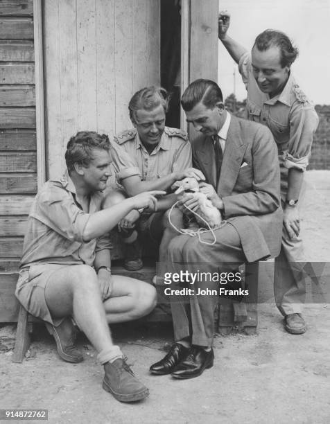 From left to right, actors Donald Houston and Richard Attenborough, producer Colin Lesslie and actor Dennis Price admiring a duck on the set of the...
