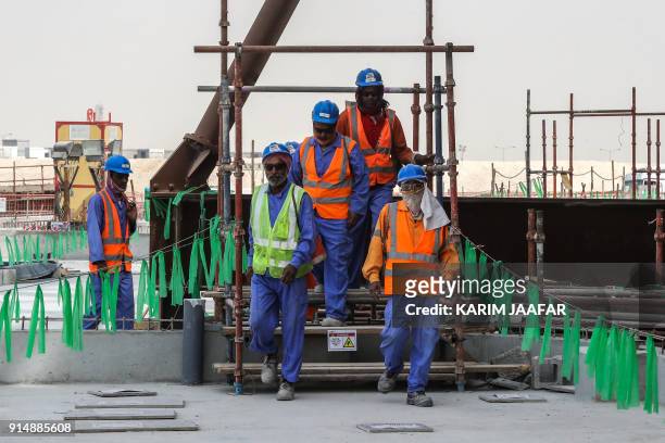 Picture taken on February 6 shows workers posing on the construction site at Al-Wakrah Stadium , a World Cup venue designed by celebrated...