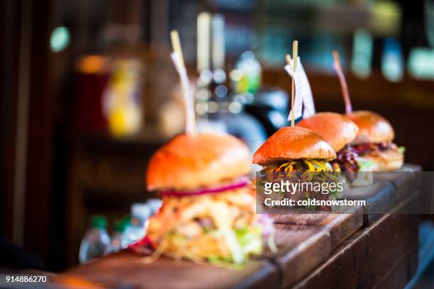 close up of fresh flame grilled burgers displayed in a row at food market - gourmet stock pictures, royalty-free photos & images