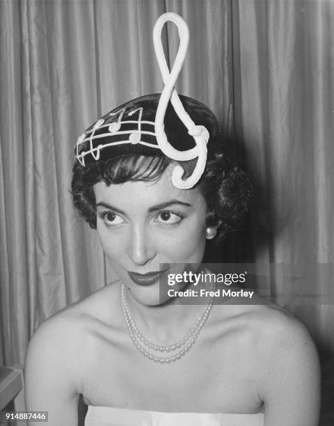 Actress Margo Lorenz wearing a 'Treble Clef' hat from Madge Chard's new collection, inspired by the MGM film 'Rhapsody', London, 28th June 1955. The...