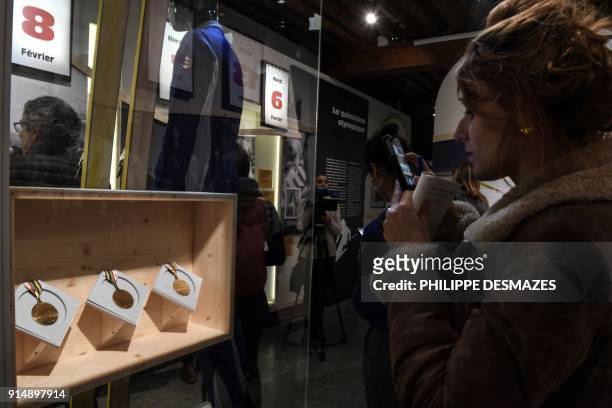 Woman takes picture of the three gold medals won by former French alpine skier Jean-Claude Killy during the 1968's Olympics Winter Games in Grenoble,...