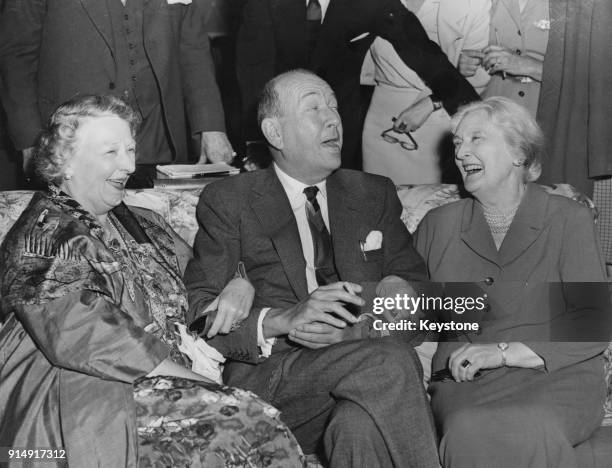 English playwright Noël Coward meets Marie Lohr and Dame Sybil Thorndike , two members of the cast of his new play 'Waiting in the Wings' at the...
