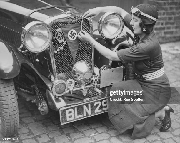 British racing driver Betty Haig , the niece of Field Marshal Earl Haig, fastens a swastika to the front of her car before the German Olympic...