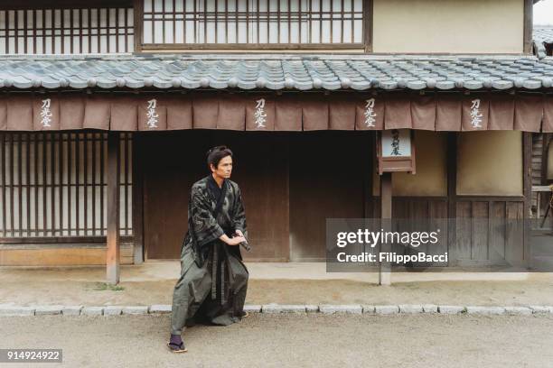 samurai walking in a traditional japanese village - samurai sword stock pictures, royalty-free photos & images