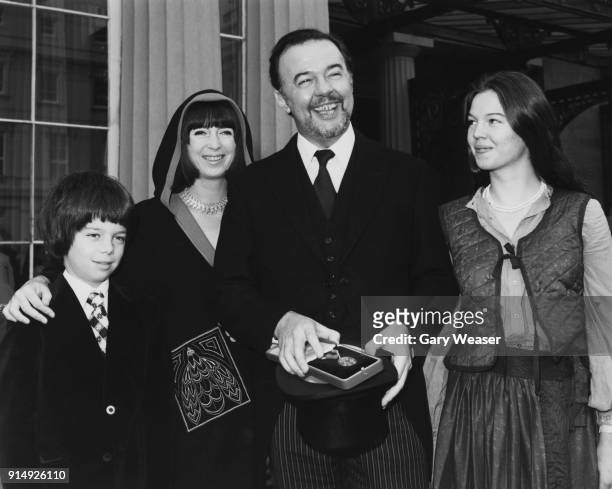 English theatre director Sir Peter Hall receives his knighthood at Buckingham Palace in London, accompanied by his second wife Jacqueline Taylor,...