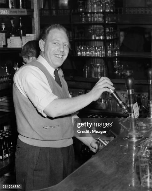 Willie Hall , a former footballer for Tottenham Hotspur and England, draws a pint at the Archers pub in Stepney, east London, 21st December 1954....