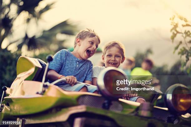 kids having extreme fun in amusement park roller coaster - parque de diversões edifício de entretenimento imagens e fotografias de stock