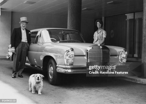 English bandleader and impresario Jack Hylton leaves London for the Epsom races in his turquoise Mercedes Benz 220 SEC coupé with his daughter...