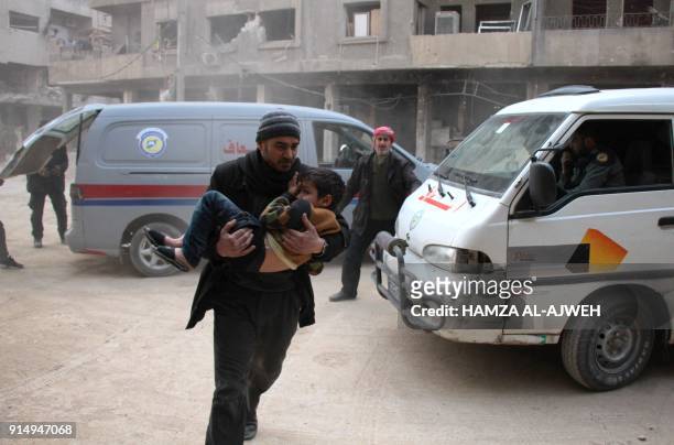 Syrian man carries a boy who was injured in reported air strikes on the rebel-held besieged town of Douma in the eastern Ghouta region, on the...