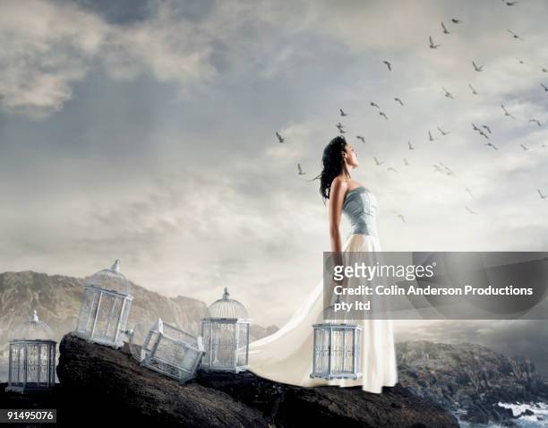 hispanic woman on cliff with empty birdcages - releasing stock pictures, royalty-free photos & images
