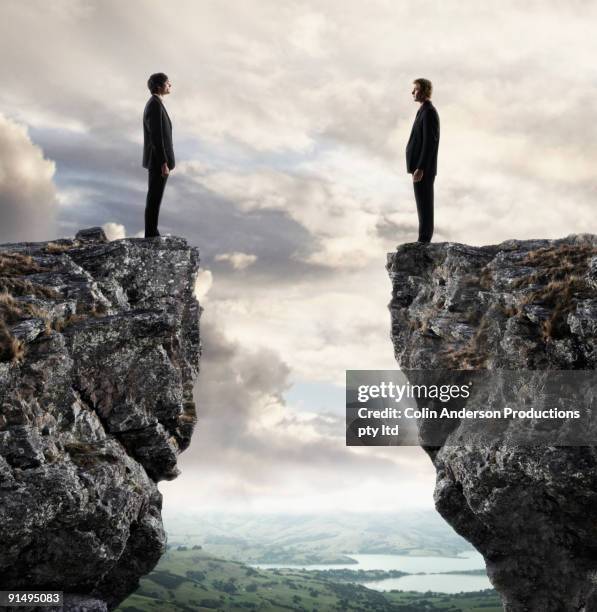 businessmen looking at each other across chasm - klippe stock-fotos und bilder