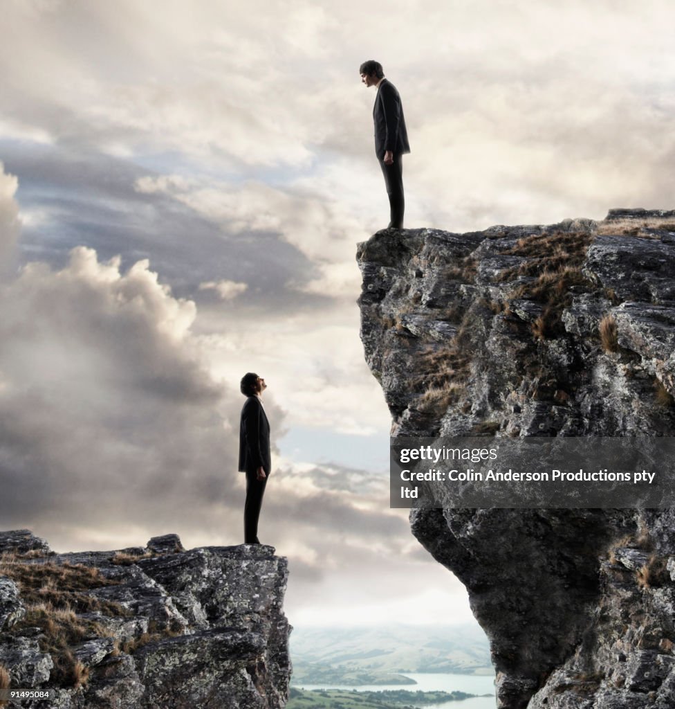 European businessmen on cliffs looking at each other