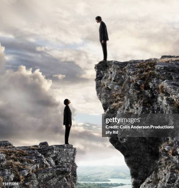 european businessmen on cliffs looking at each other - crag stock-fotos und bilder