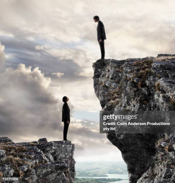 european businessmen on cliffs looking at each other - ravijn stockfoto's en -beelden