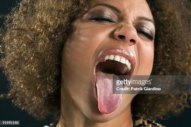 mixed race woman sticking out tongue - tongue out stockfoto's en -beelden