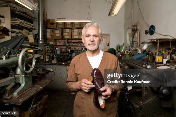 senior hispanic male cobbler holding shoe - schoenmaker stockfoto's en -beelden