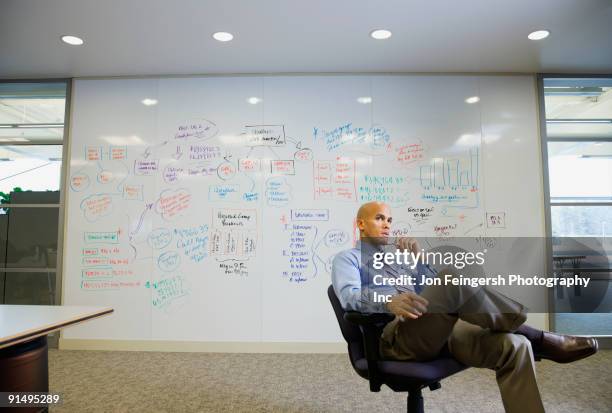 mixed race businessman sitting in front of whiteboard - visual aid stock pictures, royalty-free photos & images