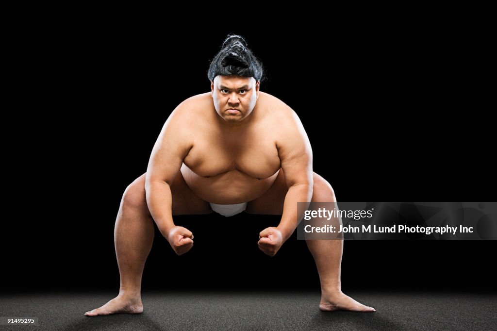 Pacific Islander sumo wrestler crouching with clenched fists