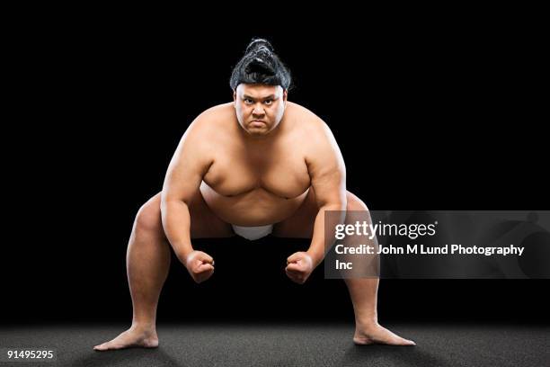 pacific islander sumo wrestler crouching with clenched fists - men wrestling stock pictures, royalty-free photos & images