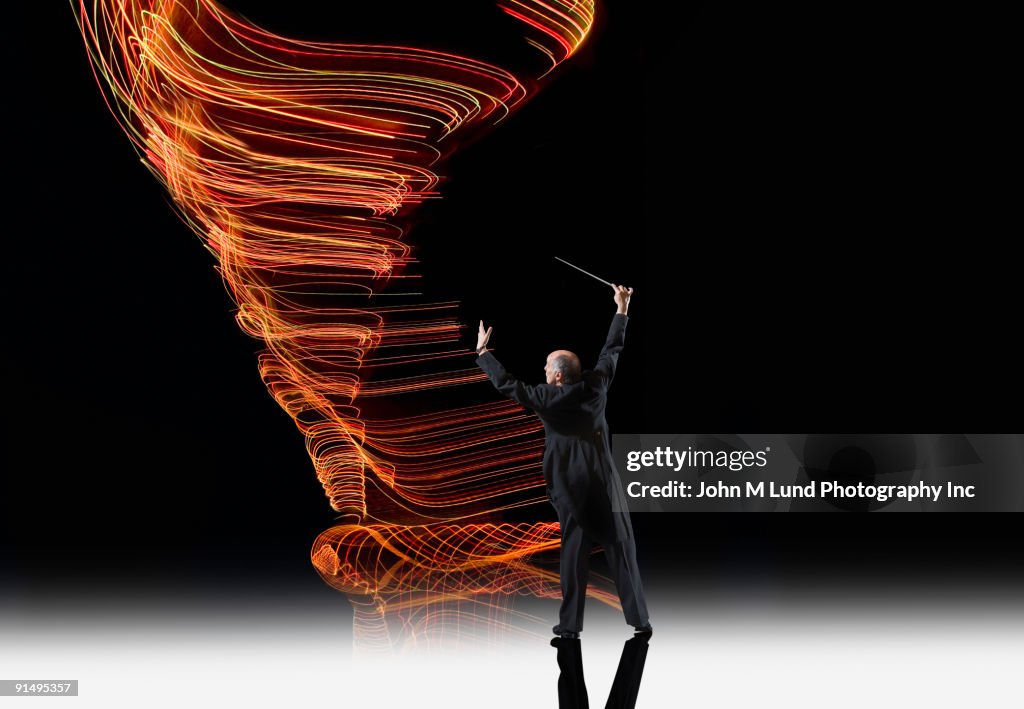 Hispanic musical conductor in front of light trails