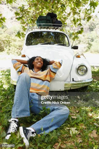 african man laying on hood of car - car camping luggage imagens e fotografias de stock