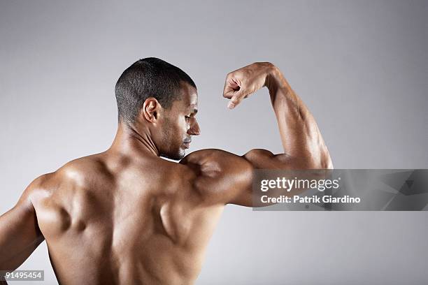 bare chested mixed race man flexing biceps - mixed race man standing studio stockfoto's en -beelden