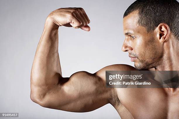 bare chested mixed race man flexing biceps - mixed race man standing studio stockfoto's en -beelden