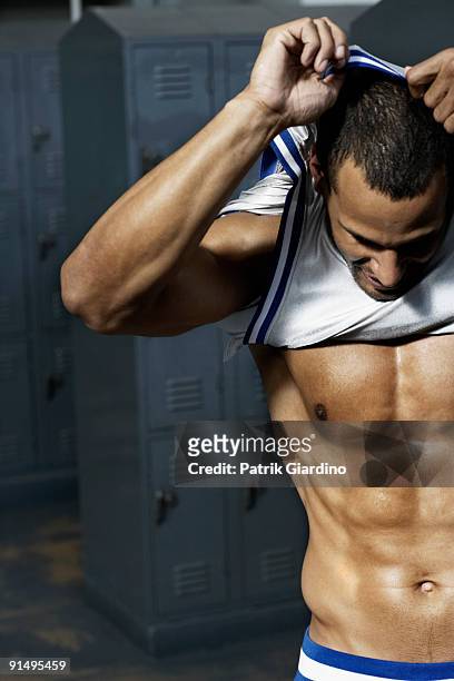mixed race basketball player undressing in locker room - trikot stock-fotos und bilder