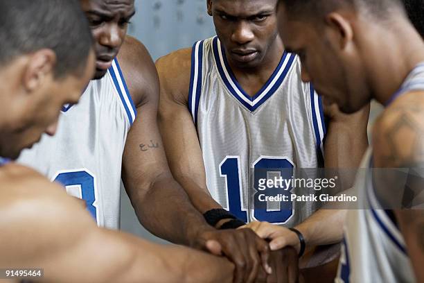 multi-ethnic basketball players huddling in locker room - basketbaltenue stockfoto's en -beelden