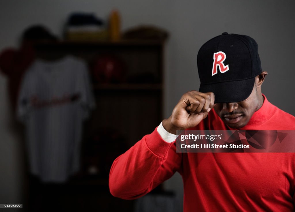 African baseball player adjusting cap in locker room