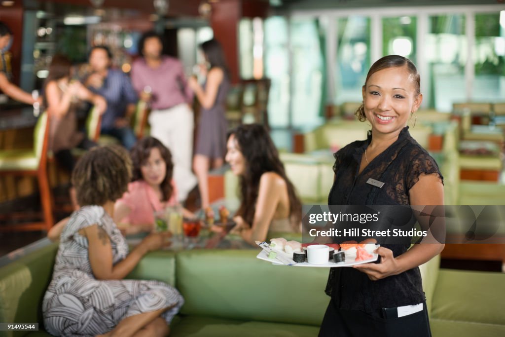 Waitress serving sushi in restaurant