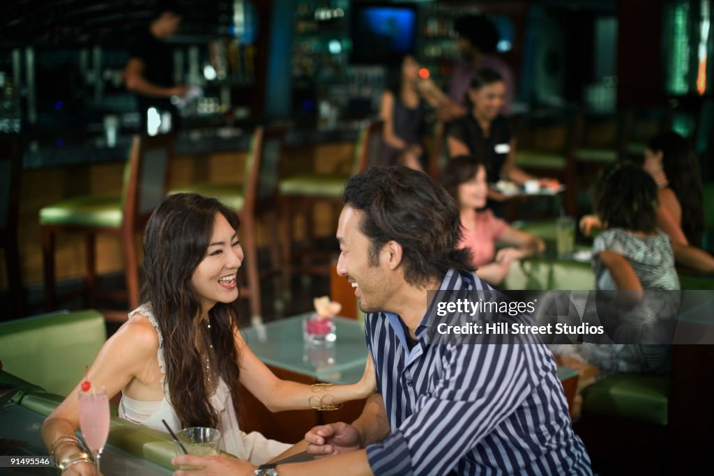 Multi-ethnic couple drinking cocktails in nightclub