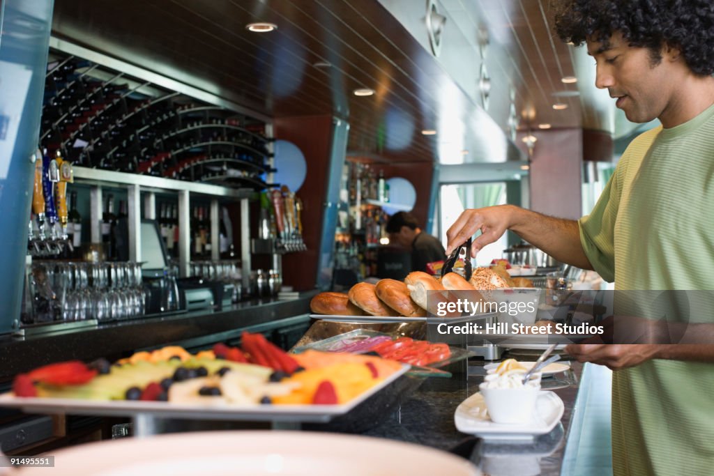 Mixed race man choosing food from breakfast buffet