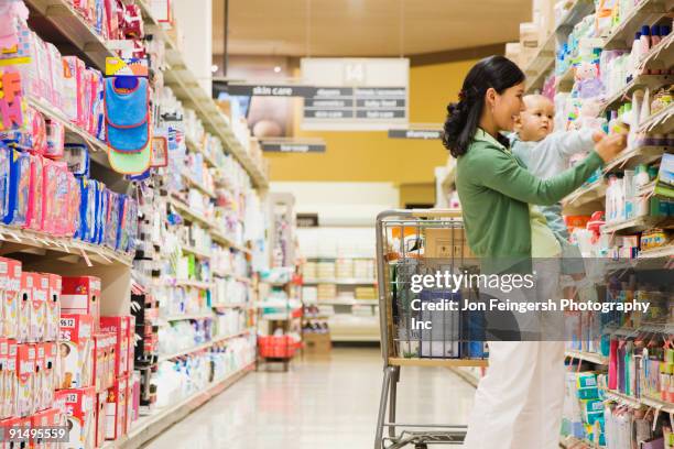 mother shopping in grocery store with baby - baby products photos et images de collection