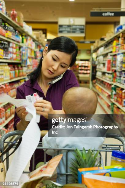 asian woman reading list in grocery store - overloaded shopping cart stock pictures, royalty-free photos & images